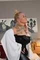 Busty blonde Frida posing in white shirt, leather corsage and black glossy leggins on bed