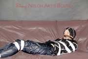 Mara wearing a sexy shiny black rian pants and a sexy shiny black rain jacket tied and gagged with tape and cloth gag on a sofa (Pics)