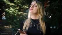 Blond lady is smoking white cigarette outdoors