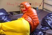 Pia tied and gagged on bed wearing a yellow rain pants and an orange downjacket (Pics)