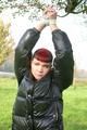 Jill tied and gagged outdoor on a tree wearing a sexy black downjacket and a black rain pants (Pics)