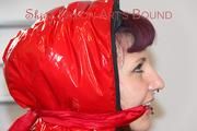 Mara tied and gagged on bed wearing a sexy shiny red down jacket and a blue rain pants (Pics)