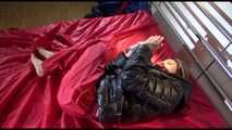 Sonnja wearing a sexy red rain pants and a black down jacket tied and gagged with a pillory and cuffs on bed (Video)