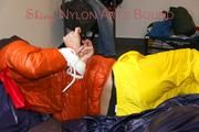 Pia tied and gagged on bed wearing a yellow rain pants and an orange downjacket (Pics)