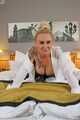 Busty blonde Frida posing in white shirt, leather corsage and black glossy leggins on bed