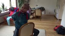 Mara tied and gagged on a chair with a bar wearing a sexy blue shiny nylon rain pants and a green rain jacket (Video)