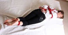 Topless barefoot Polina in unbuttoned white shirt and black jeans, bound with red ropes, poses on the floor
