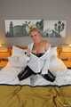 Busty blonde Frida posing in white shirt, leather corsage and black glossy leggins on bed