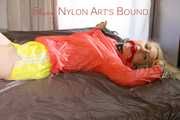 Mara tied and gagged with chains and cuffs on a bed wearing a superhot yellow shiny nylon shorts and an orange rain jacket (Pics)