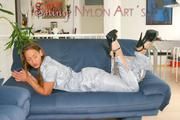 Stella posing in a living room wearing a supersexy grey rainwear jumpsuit (Pics)