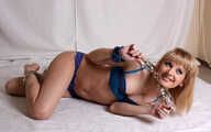 Dolly: cleave-gagged blonde barefoot girl in blue bikini, hog-cuffed with steel handcuffs and legcuffs, rolls and wiggles on the floor