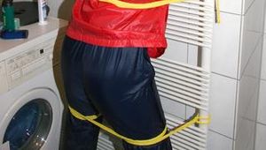 Stella tied, gagged and hooded on an radiator wearing a shiny red/blue rain combination (Pics)