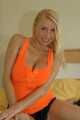 Blonde Anna in organgenem Top und Hotpants mit Öl auf dem Bett