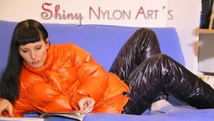 Mara wearing a sexy black down pants and an orange down jacket while lolling and reading on the sofa (Pics)