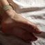 Topless barefoot Cheryl, lying under a blanket, is getting herself gagged and hogtied by a man