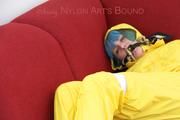 Mara tied, gagged and hooded with tape on a red sofa wearing shiny yellow rainwear (Pics)