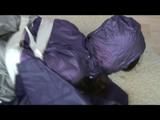 A video with Alina tied and gagged in a shiny purple and silver PVC suit