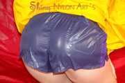 Sonja wearing a sexy blue/purple own designed shiny nylon shorts and a yellow rain jacket posing on the red sofa (Pics)