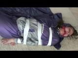 A video with Alina tied and gagged in a shiny purple and silver PVC suit
