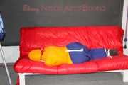 Lucy tied and gagged on a sofa wearing an orange shiny nylon rain jacket and a blue rain pants (Pics)