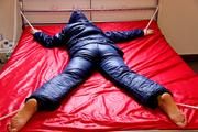 Pia hooded, tied and gagged on bed in a dark blue old school down ski suit