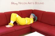 Mara tied, gagged and hooded with tape on a red sofa wearing shiny yellow rainwear (Pics)