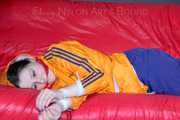 Lucy tied and gagged on a sofa wearing an orange shiny nylon rain jacket and a blue rain pants (Pics)