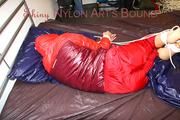 Pia tied and gagged on bed wearing a shiny red rain pants and a shiny red/purple down jacket (Pics)
