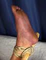 Tapegagged barefoot Bianca, hogtied with her knees tied together, but with her feet spread withe and tied to wooden stick, wiggles on the bed