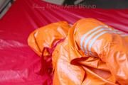 Pia tied and gagged in bed in a orange rainsuit and a red gag (Pics)