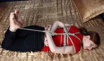 Ballgagged barefoot Tammy in red t-shirt and black jeans, hogtied with hemp rope