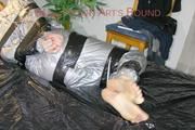Pia tied and gagged with tape on a bed wearing a sexy silver rainwear combination (Pics) 