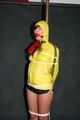 Alina tied and gagged to a pole in nylon shorts and yellow cagoule