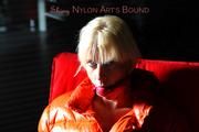 Pia tied and gagged on a chair wearing a shiny orange down jacket and a shiny blue rain pants (Pics)