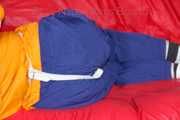 Lucy tied and gagged on a sofa wearing an orange shiny nylon rain jacket and a blue rain pants (Pics)