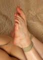 Tapegagged barefoot Doris in black bra and panties, hogtied with hemp rope, wiggles on the mattress