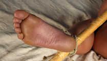 Tapegagged barefoot Bianca, hogtied with her knees tied together, but with her feet spread withe and tied to wooden stick, wiggles on the bed