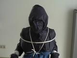 An archive girl tied, gagged and hooded two times on a sofa and chair wearing a shiny blue rainwear (Video)