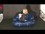 Blonde archive girl posing on a blowable chair wearing shiny nylon shorts and a rain jacket (Video)