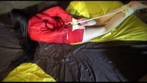 Lucy tied and gagged on bed wearing a red/yellow shiny nylon shorts and a red rain jacket (Video)