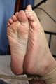 Ballgagged barefoot Carolyn, hogtied with hemp rope, wiggles on the bed