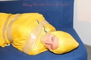 Archive girl tied and gagged by using tape on a sofa wearing an yellow rainsuit (Pics)
