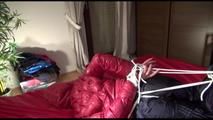 Lucy tied and gagged on bed wearing a sexy black shiny nylon pants and a red down jacket (Video)