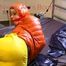 Pia tied and gagged on bed wearing a yellow rain pants and an orange downjacket (Pics)