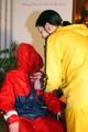 Jill tied by her friend in shiny yellow and red rainsuits