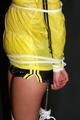 Alina tied and gagged to a pole in nylon shorts and yellow cagoule